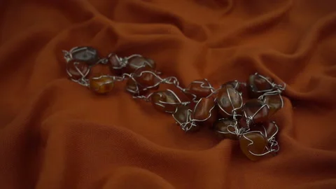 Falling gems jewel on a rust colored soft fabric in slow motion. Stock Footage 120129074