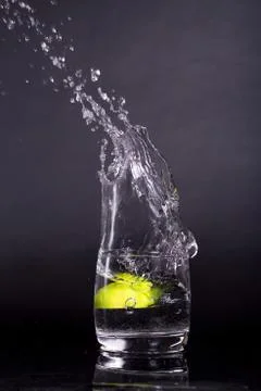 Falling in a glass of lemon, lime, splash on black background, isolated, wate Stock Photos