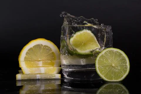 Falling in a glass of lemon, lime, splash on black background, isolated, wate Stock Photos