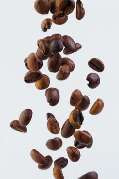 Falling grains of roasted coffee on a white background Stock Photos