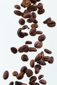 Falling grains of roasted coffee on a white background Stock Photos