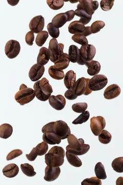 Falling grains of roasted coffee on a white background Stock Photos
