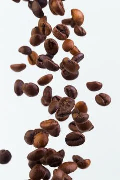Falling grains of roasted coffee on a white background Stock Photos