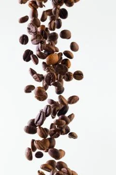 Falling grains of roasted coffee on a white background Stock Photos