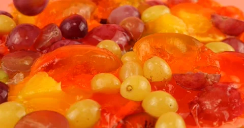 Falling grapes on a multi-colored berry gelatin jelly with orange and kiwi slice Stock Footage 219970134