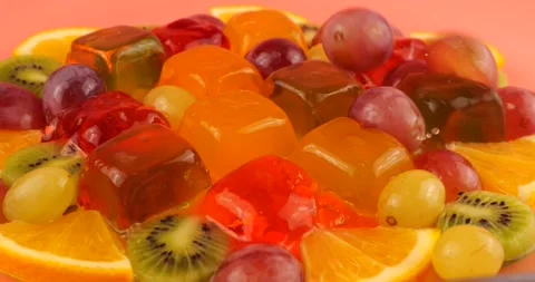 Falling grapes on a multi-colored berry gelatin jelly with orange and kiwi slice 動画素材 219970203
