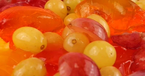 Falling grapes on a multi-colored berry gelatin jelly with orange and kiwi slice Stock Footage 220125479