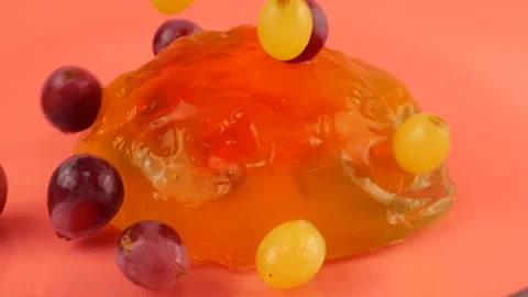 Falling grapes on a multi-colored gelatin jelly on a pink background. Stock Footage 219969662