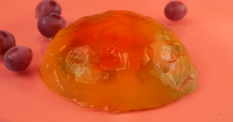 Falling grapes on a multi-colored gelatin jelly on a pink background. Stock-Footage 219970219