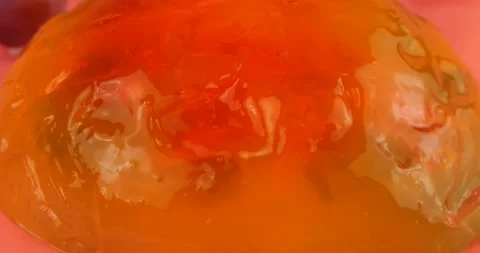 Falling grapes on a multi-colored gelatin jelly on a pink background. Stock-Footage 220125620