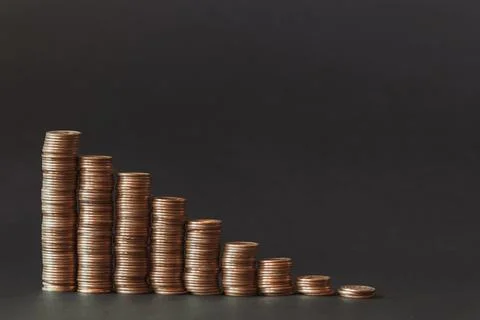 Falling graph in the form of gold coins on a black background. Stock Photos