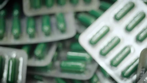 Falling green capsule pills in blister pack. Drug manufacturing, macro Stock Footage 102464821