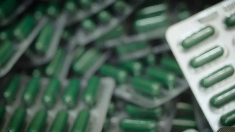 Falling green capsule pills in blister pack. Drug manufacturing, macro Stock Footage 102465337