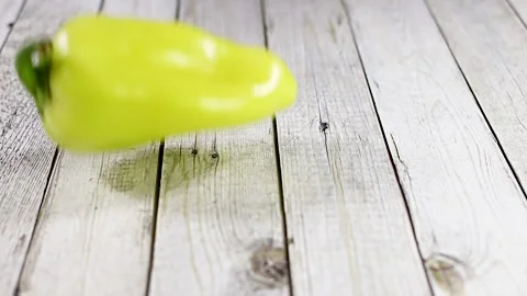 Falling green pepper on wooden table. Slow motion Stock Footage 140234017