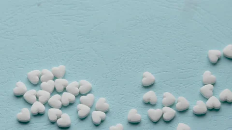 Falling hearts shape little cute pills on blue paper background Vídeo Stock 208856746