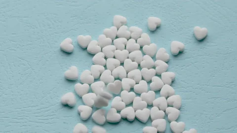 Falling hearts shape little cute pills on blue paper background 動画素材 208857035