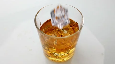 Falling ice cube into whisky drink glass Stock Footage 202970761