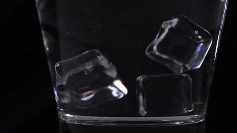 Falling ice cubes into a glass with clear water on black background Stock Footage 169594368