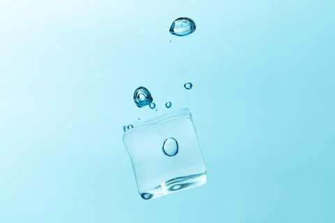 Falling ice cubes in water splashes isolated on blue background. Foto stock