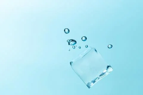 Falling ice cubes in water splashes isolated on blue background. Stock Photos