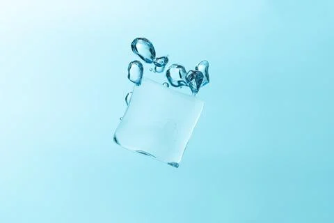 Falling ice cubes in water splashes isolated on blue background. Stock Photos