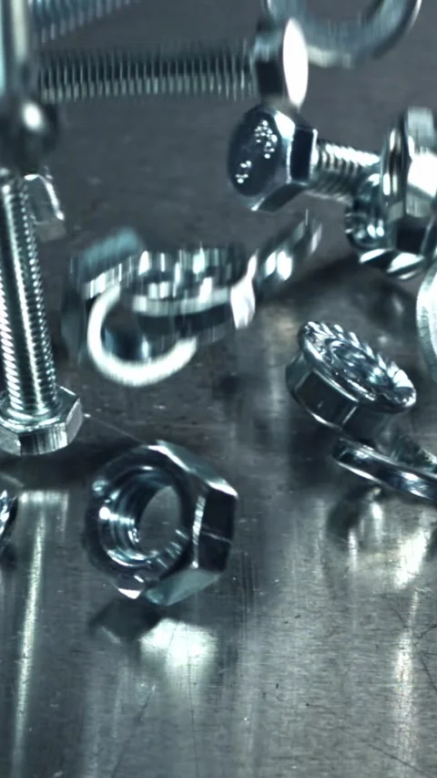 Falling nuts, bolts and washers on a metal table. Filmed on a high-speed camera Stock Footage 335363702