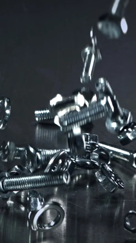 Falling nuts, bolts and washers on a metal table. Filmed on a high-speed camera Stock Footage 335364707