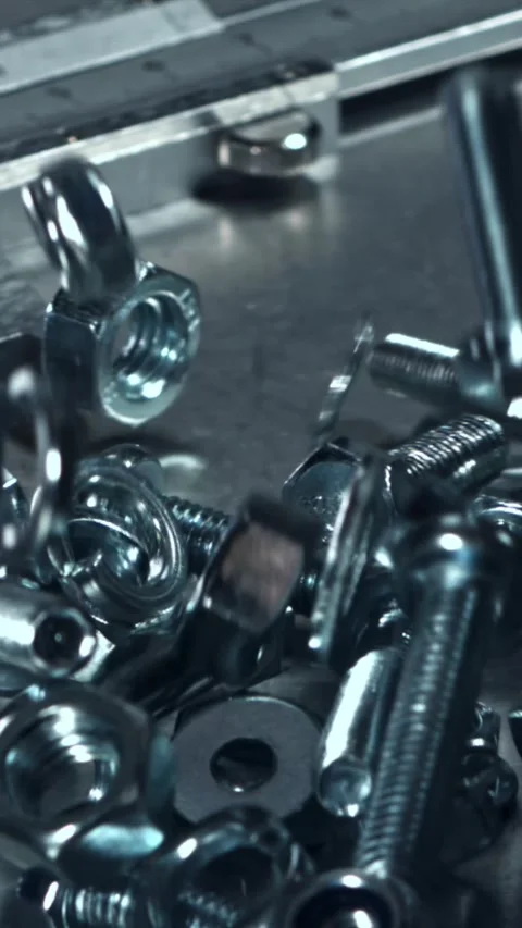 Falling nuts, bolts and washers on a metal table. Filmed on a high-speed camera Stock Footage 335365624