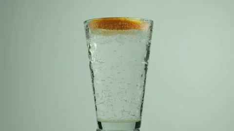 Falling orange slice into a glass of sparkling water and many drops and splashes Stock Footage 153431796
