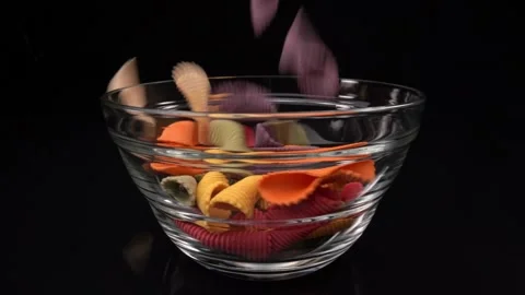 Falling pasta in the form of a shell in macro shot in super slow motion into a Video stock 231404026