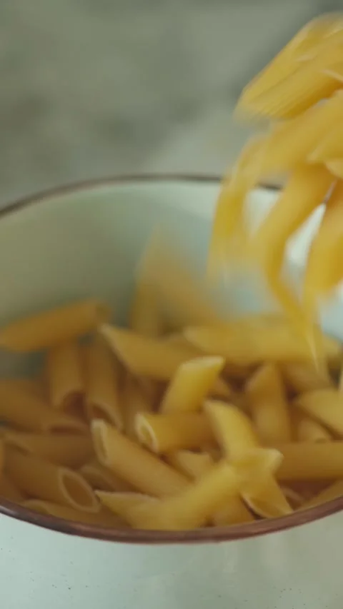 Falling Penne Rigate Pasta into Ceramic Bowl Vertical Video Stock Footage 314925700