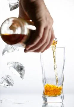 Falling pieces of ice and a hand pouring alcohol into a glass Stock Photos
