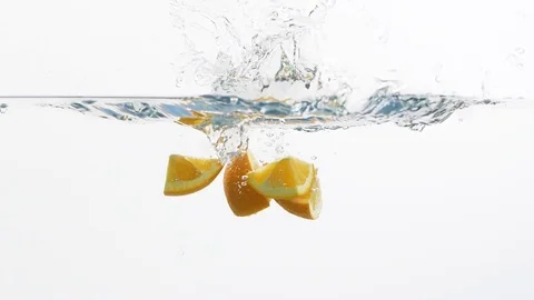 Falling pieces of orange into a water Stock Footage 99724348