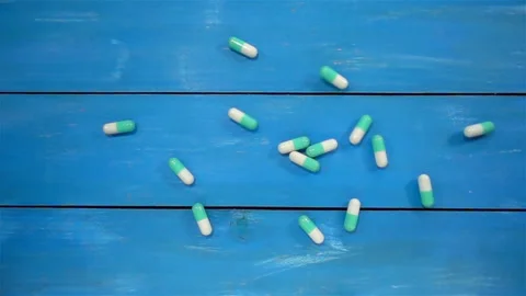 Falling pills in slow motion on a blue Stock Footage 140470901