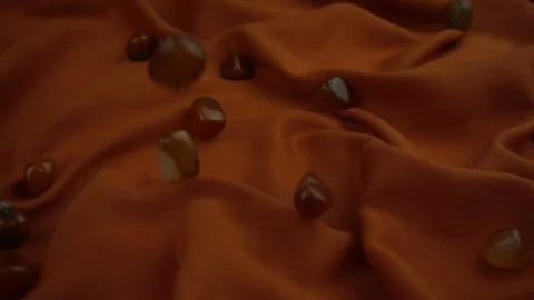 Falling processed gems jewel on a gorgeous rust colored soft fabric in slow moti Stock Footage 120129384