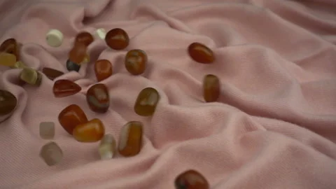 Falling processed gems jewel on a gorgeous pastel pink soft fabric in slow motio Stock Footage 120190229