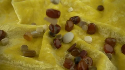 Falling processed gems jewel on a soft velvet yellow colored fabric in slow moti Stock Footage 121112146