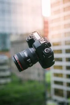 A falling professional camera captured in the air with blurred architecture i Fotos de archivo