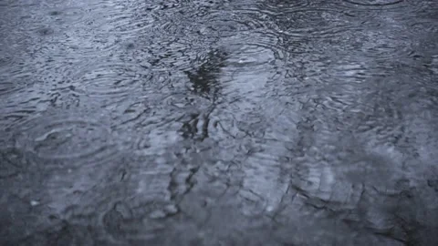 Falling rain drops on reflected puddle in slow motion. Water drops. Stock Footage 154923007