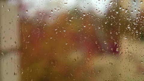 Falling rain drops on window surface close-up. Natural autumn red and yellow Stock Footage 254197772