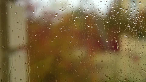 Falling rain drops on window surface close-up. Natural autumn red and yellow Stock Footage 279541259