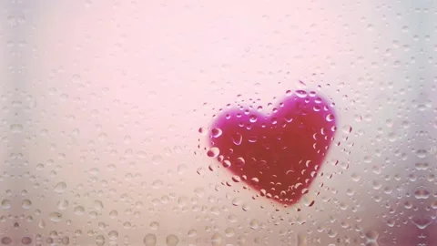 Falling Rain with Mist and Drops of Water on Glass. Heart in the Background. Stock Footage 131047348