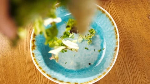 Falling salad in slow motion. Chef puts green leaves of salad in the plate. Stock Footage 133416452