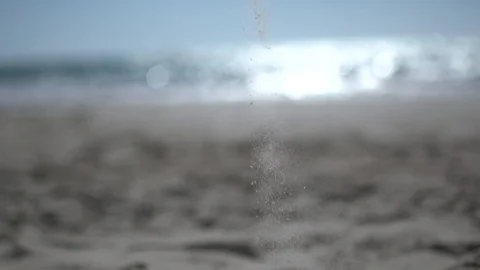 Falling sand at the beach, shot against the sun flare sandy beach slow motion Stock Footage 100165362