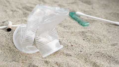 Falling sea garbage,cotton swabs,razor blade and cigarettes discarded on beach Stock Footage 143392602