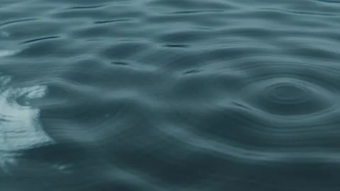 Falling single drop hitting teal water under panel lights, revealing expanding Stock Footage 339722012