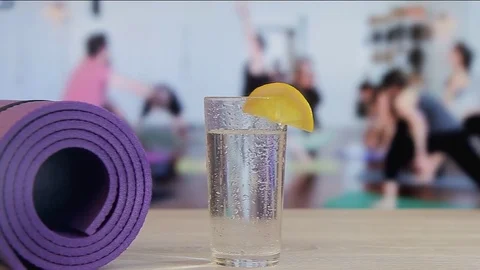Falling of a slice of a lemon in a glass with water, yoga, pilates, group Stock Footage 74209443