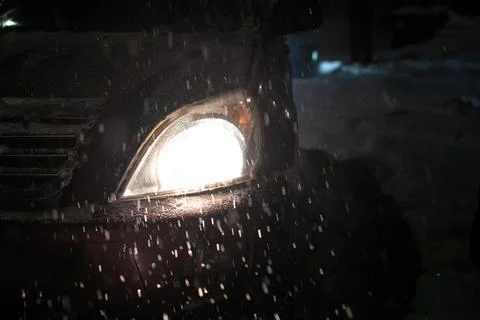 Falling snow on the background of the glowing headlights of the car, during a Stock Photos