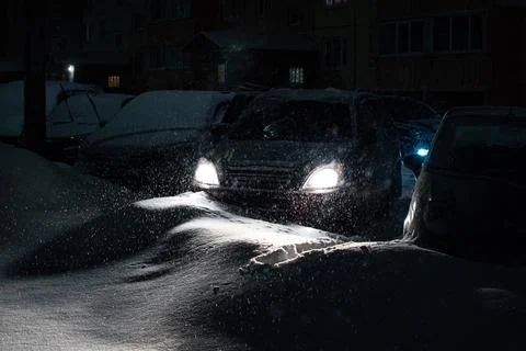 Falling snow on the background of the glowing headlights of the car, during a Stock Photos
