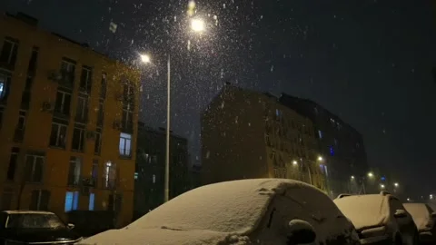 Falling snow backlit with modern street lamp in city street at night in winter. Stock Footage 183965658